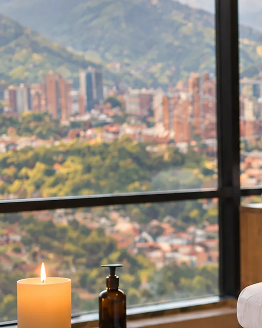 Vela y aceite junto a un ventanal con vista a las montañas del Oriente antioqueño